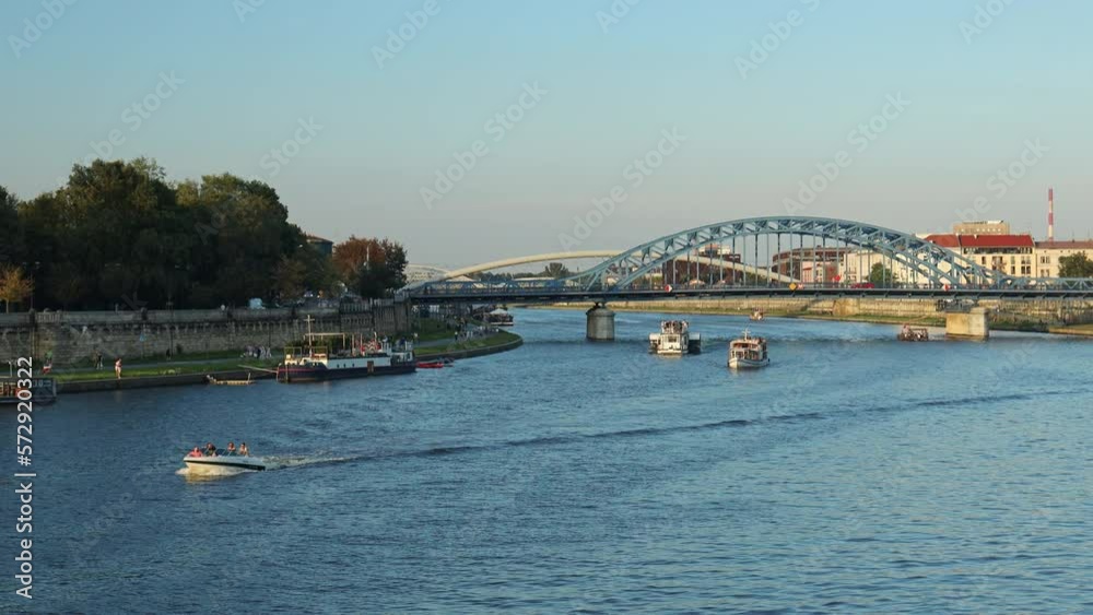4k Vistula river in Krakow, Poland with blue metal Marshal Józef Piłsudski Bridge arch bridge over at sunset