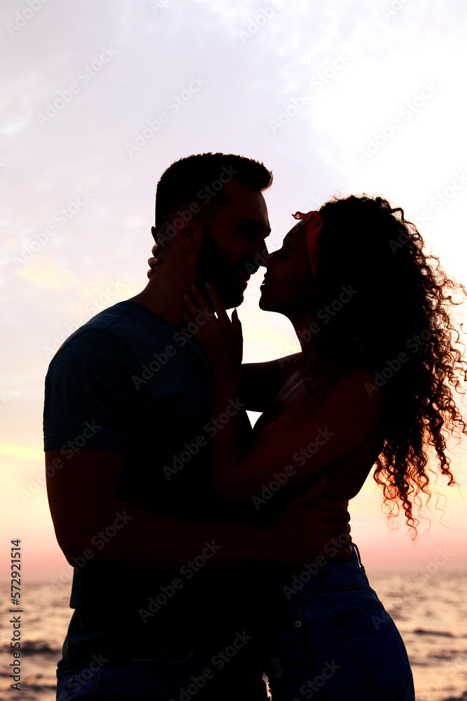 Silhouette of lovely couple spending time together near sea at sunset