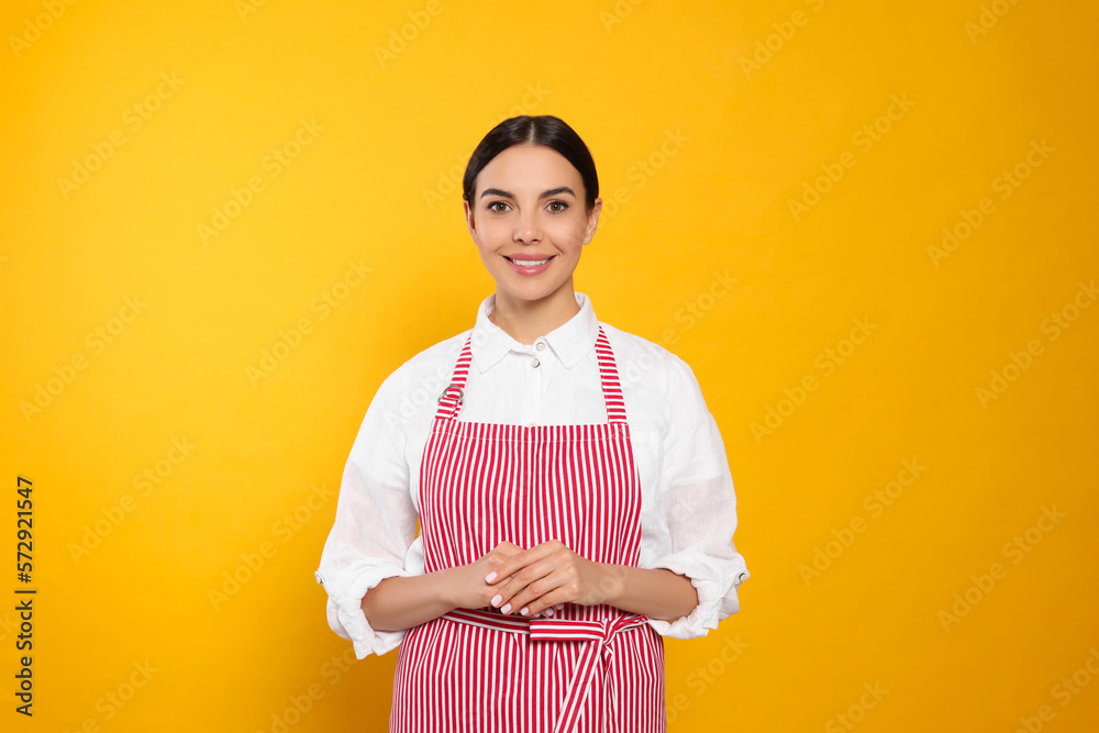 Young woman in red striped apron on yellow background Young woman in red striped apron on yellow background