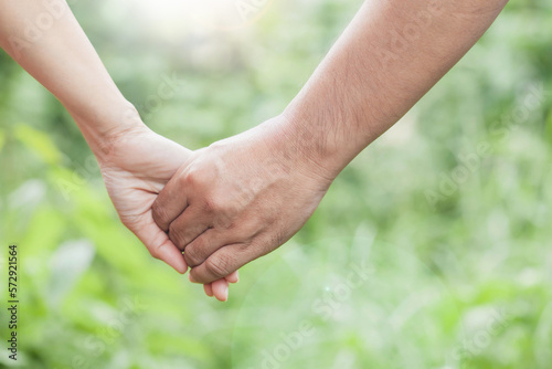 A couple holding hand together over blurred nature background,Business man and woman shaking hands,helping hand  and world peace concept with copy space © isara