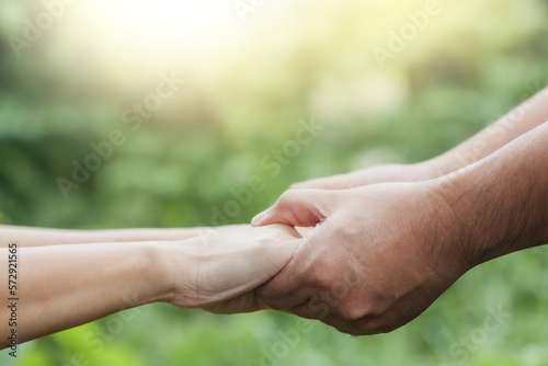 Close up of two people holding hand together over blurred nature background,Business man and woman shaking hands,helping hand  and world peace concept with copy space © isara