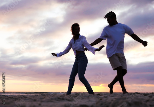 Silhouette of lovely couple dancing on beach at sunset