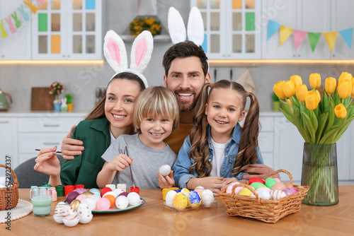 Canvas Print Portrait of happy family with Easter eggs at table in kitchen