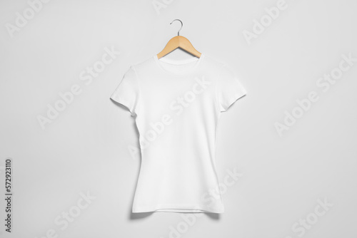 Hanger with white t-shirt on light wall. Mockup for design