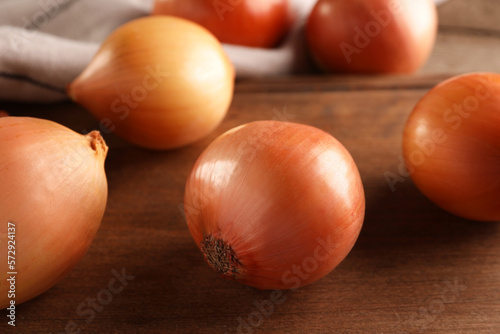 Many ripe onions on wooden table  closeup