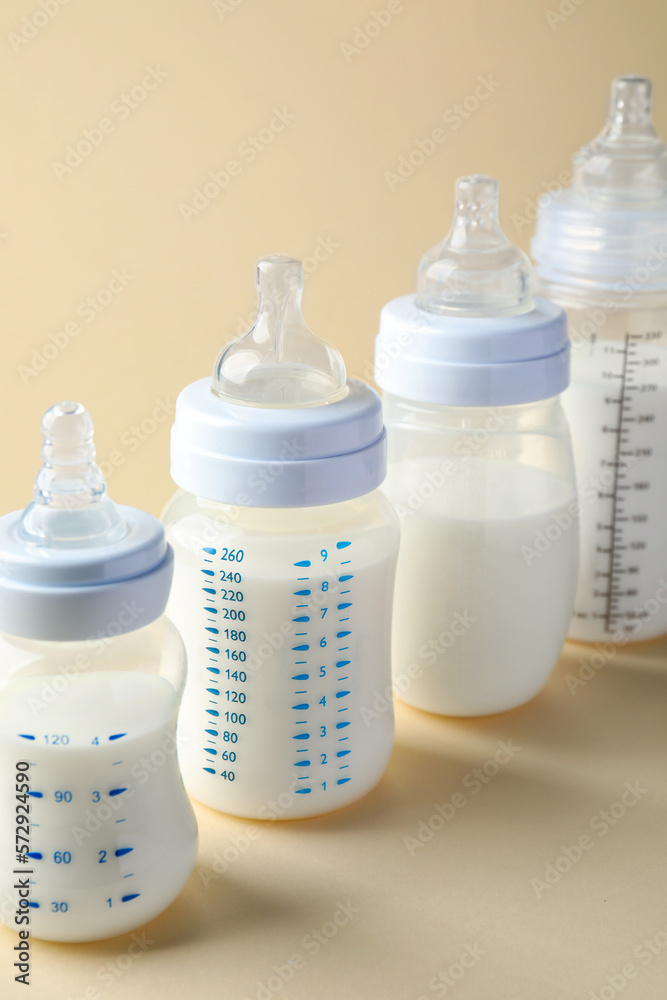 Feeding bottles with baby formula on beige background Feeding bottles with baby formula on beige background