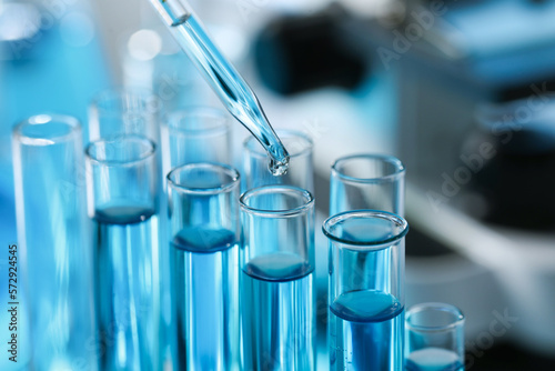 Dripping liquid from pipette into test tube in laboratory, closeup