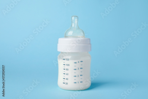 One feeding bottle with milk on light blue background