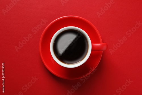 Cup with aromatic coffee on red background  top view