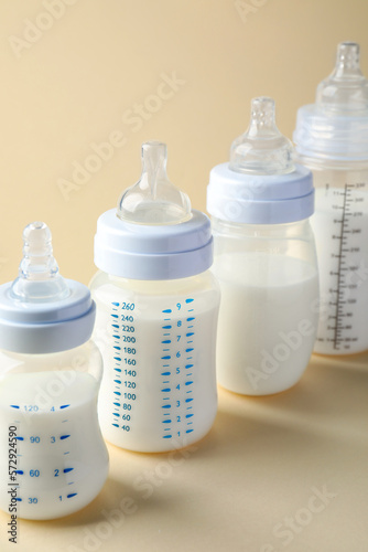 Feeding bottles with baby formula on beige background