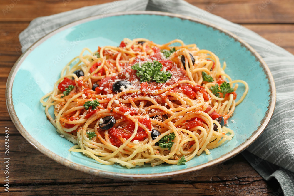 Delicious pasta with tomatoes, olives and parmesan cheese on wooden table, closeup