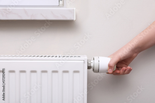 Wallpaper Mural Girl adjusting heating radiator thermostat near white wall indoors, closeup Torontodigital.ca