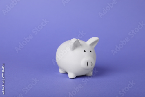Ceramic piggy bank on purple background. Financial savings © New Africa