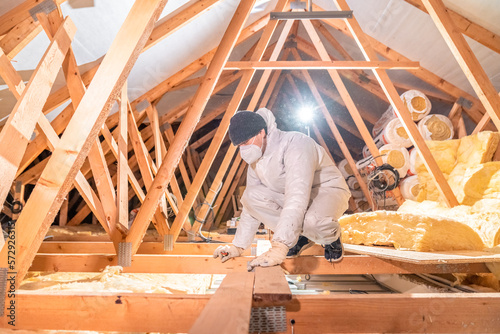 man insulates the roof and ceiling of the house with glass wool photo