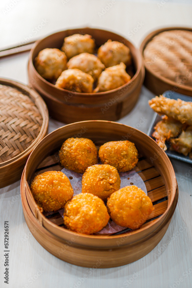 Close up of fried Dimsum in traditional bamboo basket with
chopsticks on wooden background Close up of fried Dimsum in traditional bamboo basket with
chopsticks on wooden background