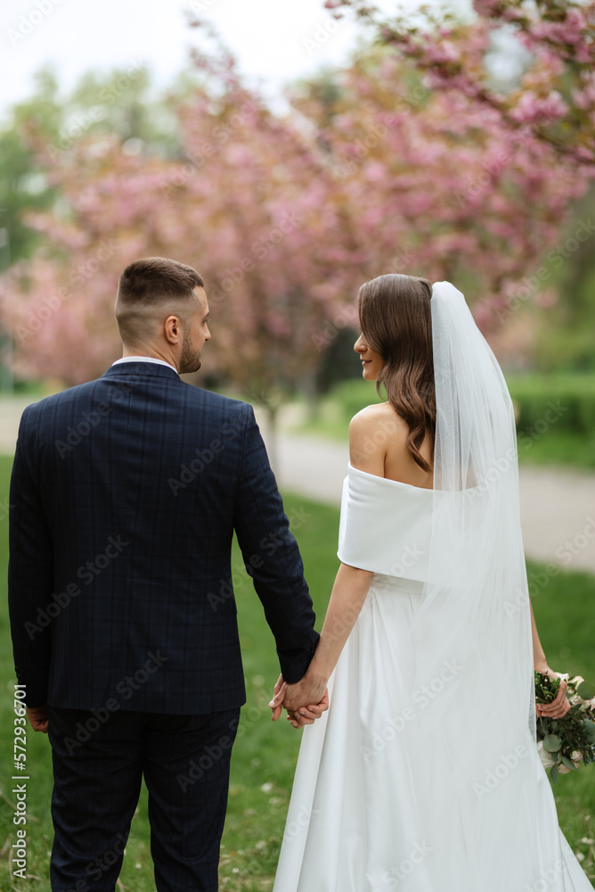 newlyweds walk in the park among cherry blossoms