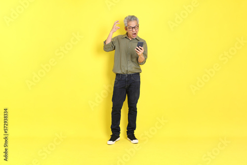 The 40s adult Asian man with casual dressed standing on the yellow background. © kimberrywood