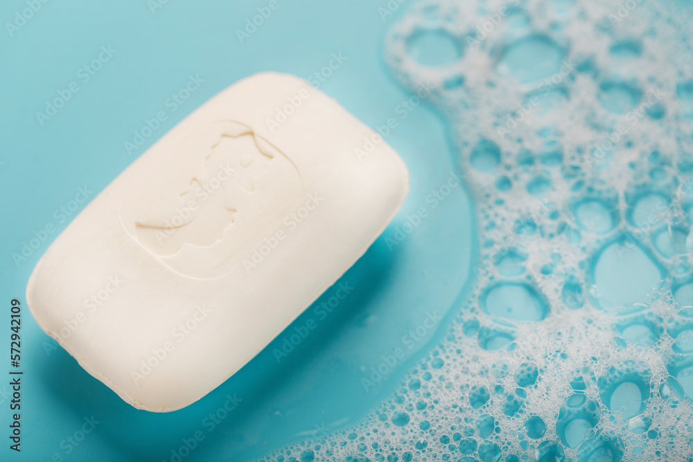 A piece of white soap with foam on blue background. Backdrop with copt space. A piece of white soap with foam on blue background. Backdrop with copt space.