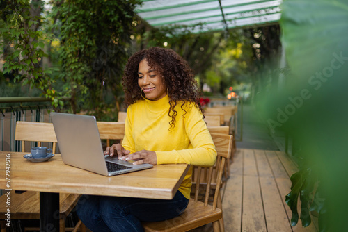 Beautiful Brazilian young woman outdoors using laptop