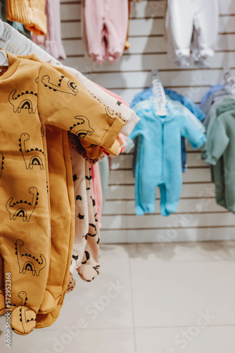 Bright spring jumpsuits for newborns hang on hangers in a children's clothing store © Katsiaryna