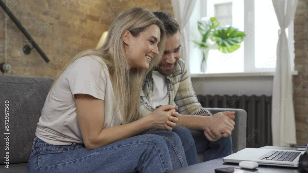 Happy couple using laptop for video call in the living room Happy couple using laptop for video call in the living room