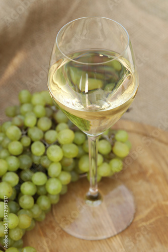 glass of white wine on wooden background with  grape
