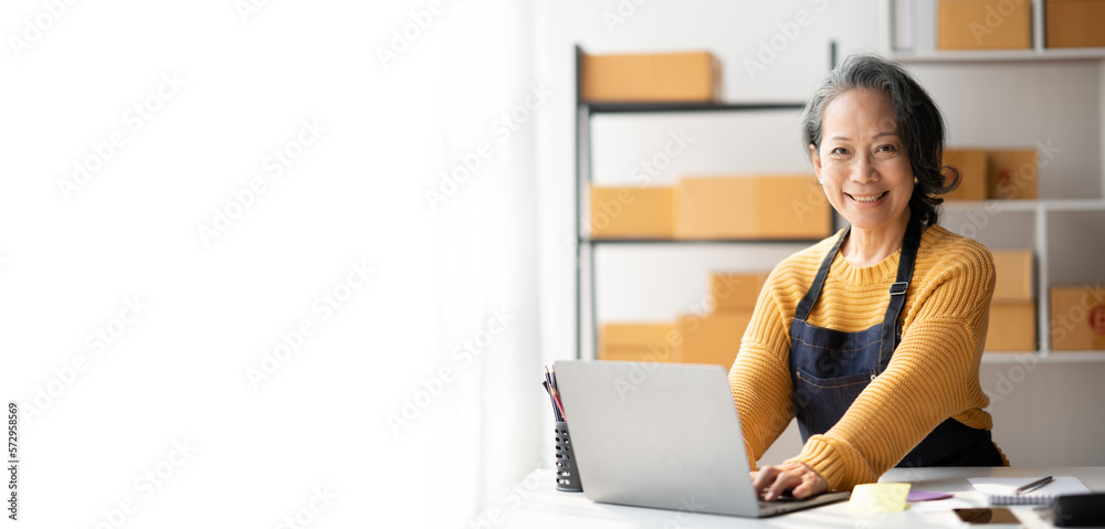 Small business owner lady working with laptop computer, typing customer details on laptop before sending the product to customer.