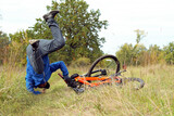 Stressed male cyclist falling from a bicycle fter a bad accident. Young man suffering a bike accident at a mountain trail
