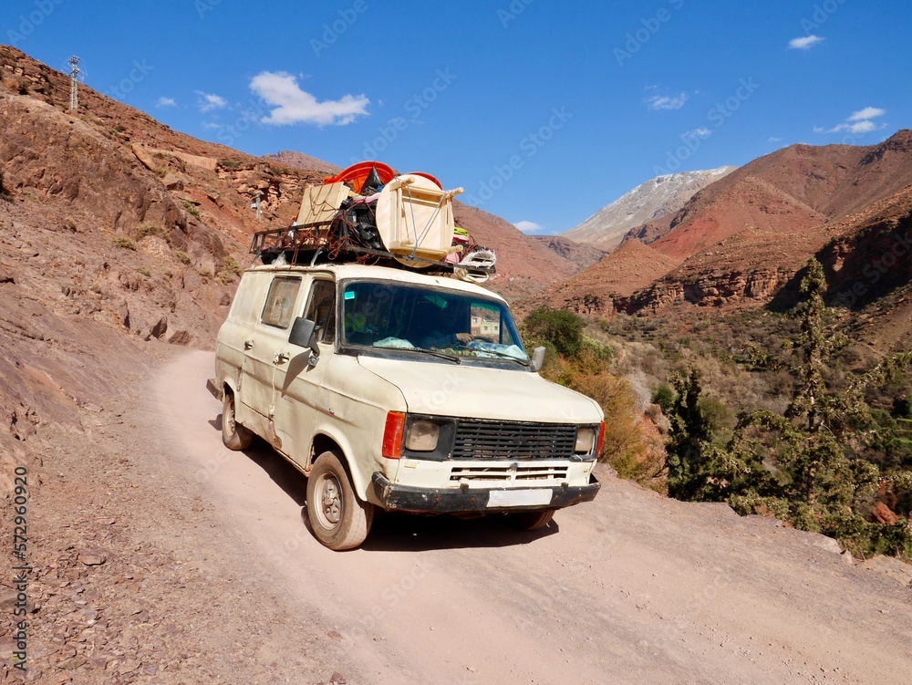 Fully loaded vintage van on off-road track in Ourika Valley, High Atlas Mountains, Morocco.