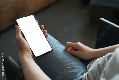 Young woman sitting in chair and holding smartphone with white screen