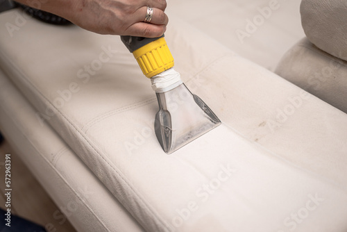 Cleaning a dirty sofa with a sofa washer. Close up of hands holding sofa cleaner. Professional sofa wash. Sofa wash image