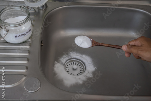 Man pouring baking soda to clear clogs in sinks and drains at home