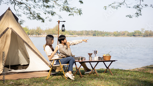 Young couple camping weekend in the woods near river, Enjoying Camping Holiday In Countryside, Leisure activities, Dating and relaxation in nature, Couple dripping coffee and sipping coffee. © Puwasit Inyavileart