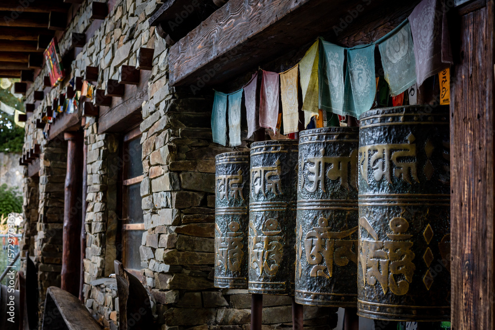 Obraz premium A row of metal tibetan buddhist prayer wheels with golden matra letters. 