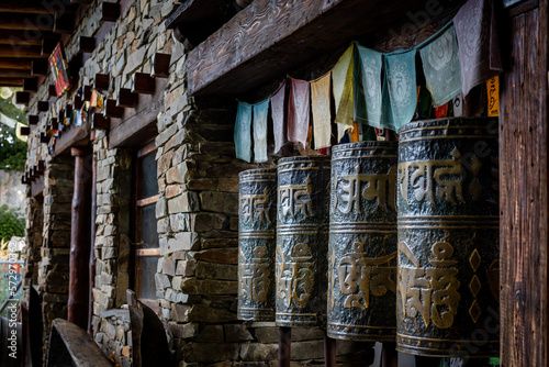 A row of metal tibetan buddhist prayer wheels with golden matra letters.  © Kati Lenart
