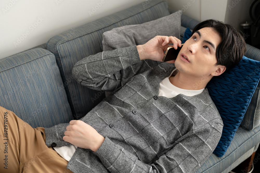 ソファで寛ぎ電話する男性 ソファで寛ぎ電話する男性