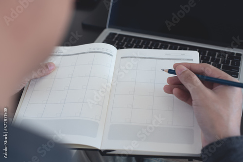 2023 Calendar event planning timetable agenda plan on organize schedule. Event planner agenda organizing by organizer schedule. Business man hand note on notebook with calendar planner on office table
