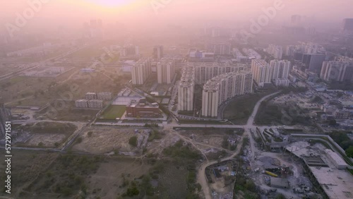 aerial drone shot moving sideways over skyscrapers with houmes office and shops with sunset rays in the distance showing the real estate in gurgaon delhi photo
