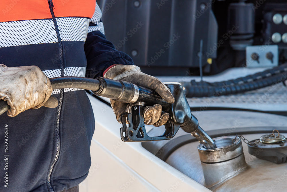 Obraz premium Truck driver with a pump nozzle in his hands filling the vehicle's fuel tank, Close-up.
