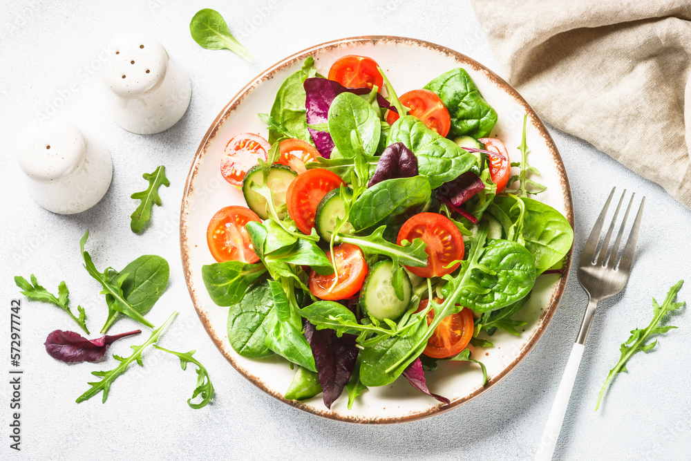 Green salad with fresh leaves and vegetables in white plate. Top view. Green salad with fresh leaves and vegetables in white plate. Top view.