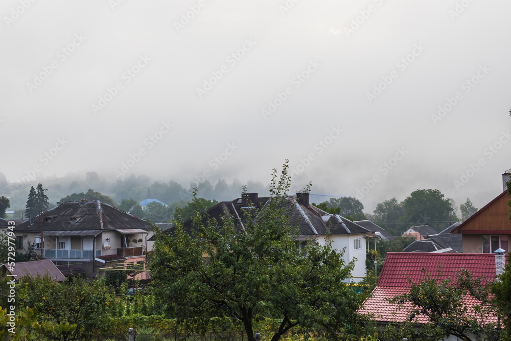 Mountain from view with small village and flow fog. Foggy summer