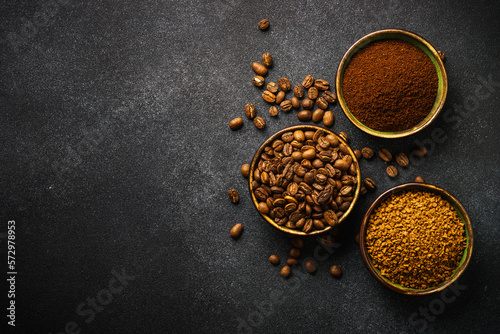 Roasted coffee beans, ground coffee and instant coffee in bowls at dark background. Top view image.