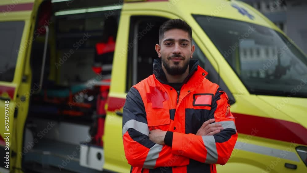 Young man doctor standing in front of ambulance car.