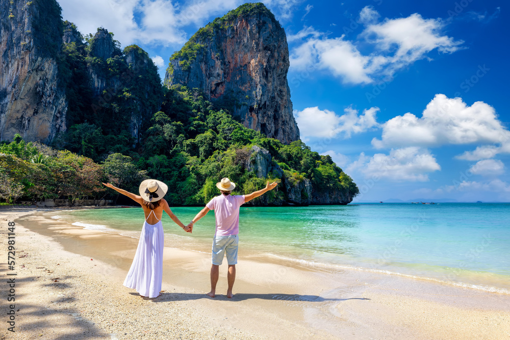 A happy couple stands on the beautiful beach of Railay, Krabi, Thailand, during their summer vacations