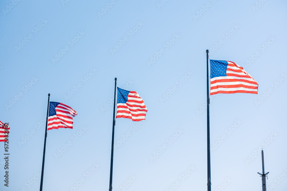 American flags blowing in the wind against bright blue sky