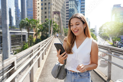 Fototapete Portrait of smiling girl on footbridge watching her smartphone in the modern sus