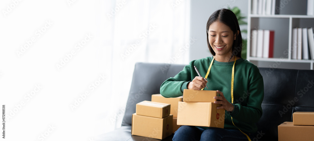 Lovely Asian business owner writing down the details of the customers on the parcel boxes before distributing to the customers. Lovely Asian business owner writing down the details of the customers on the parcel boxes before distributing to the customers.