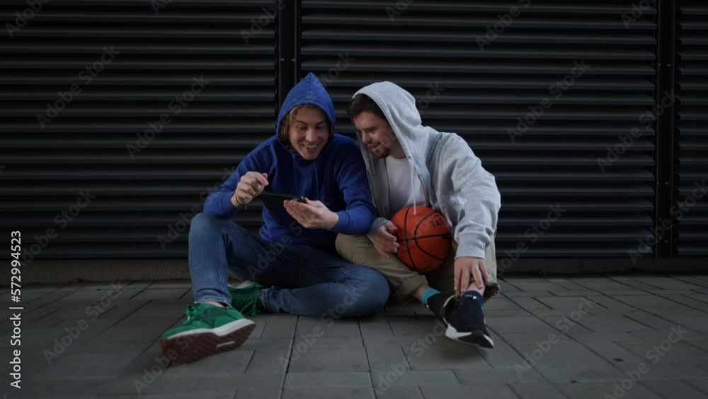Man with down syndrome resting during basketball playing outdoor with his friend. Concept of friendship and integration people with disability into society. Man with down syndrome resting during basketball playing outdoor with his friend. Concept of friendship and integration people with disability into society.