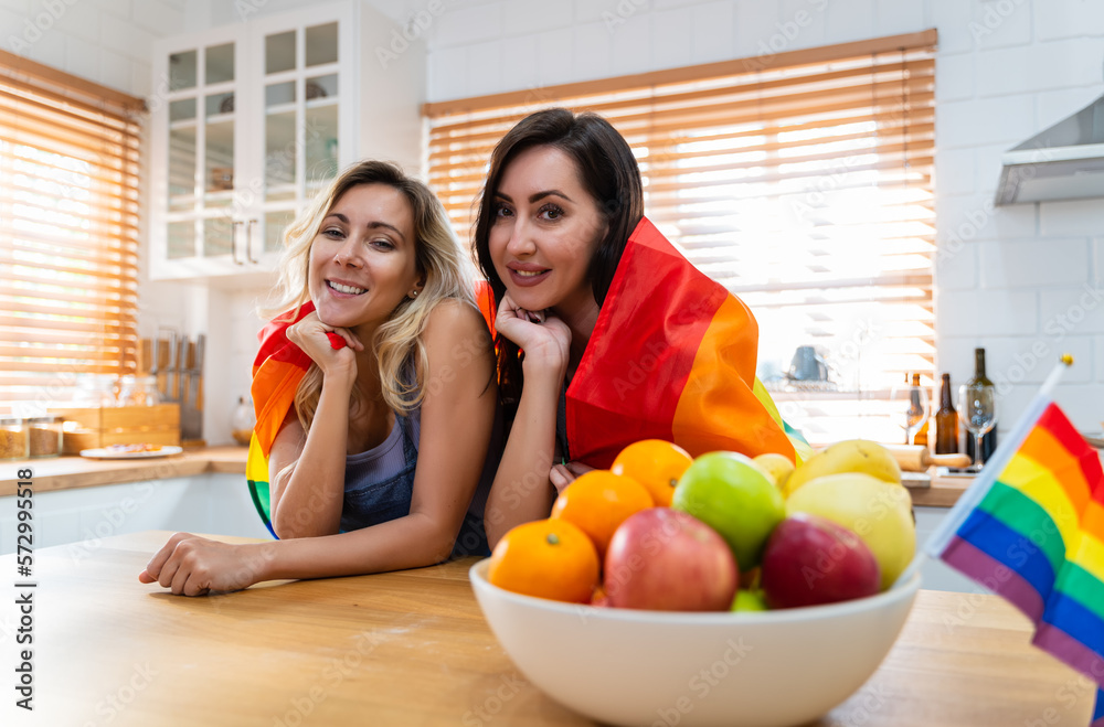 An LGBTQ caucasian couples are posing and clad in lgbtq symbolic flags