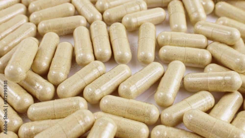 Beige medical capsules with dietary supplements inside falling down close up Beige medical capsules with dietary supplements inside falling down close up